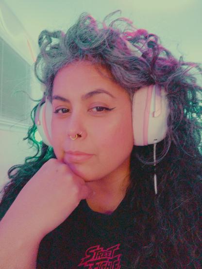 A woman with gray curly hair wearing white and pink headphones looking at the camera.