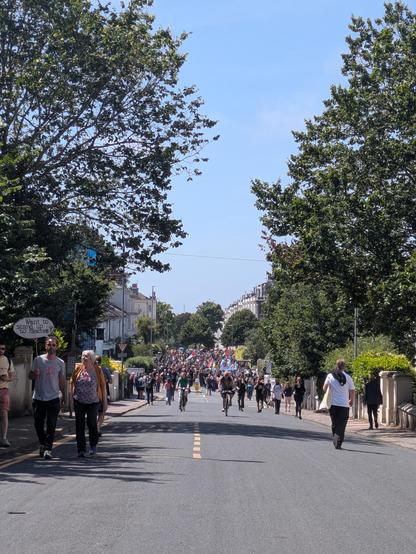 A massive crowd marching up a big street in the seven dials district of Brighton