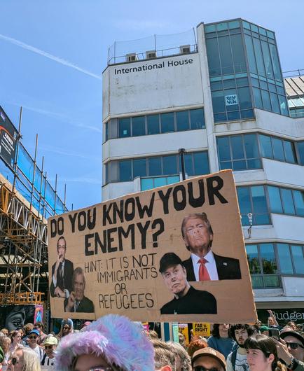 Sign with trump and musk etc with pig noses saying do you know your enemy?