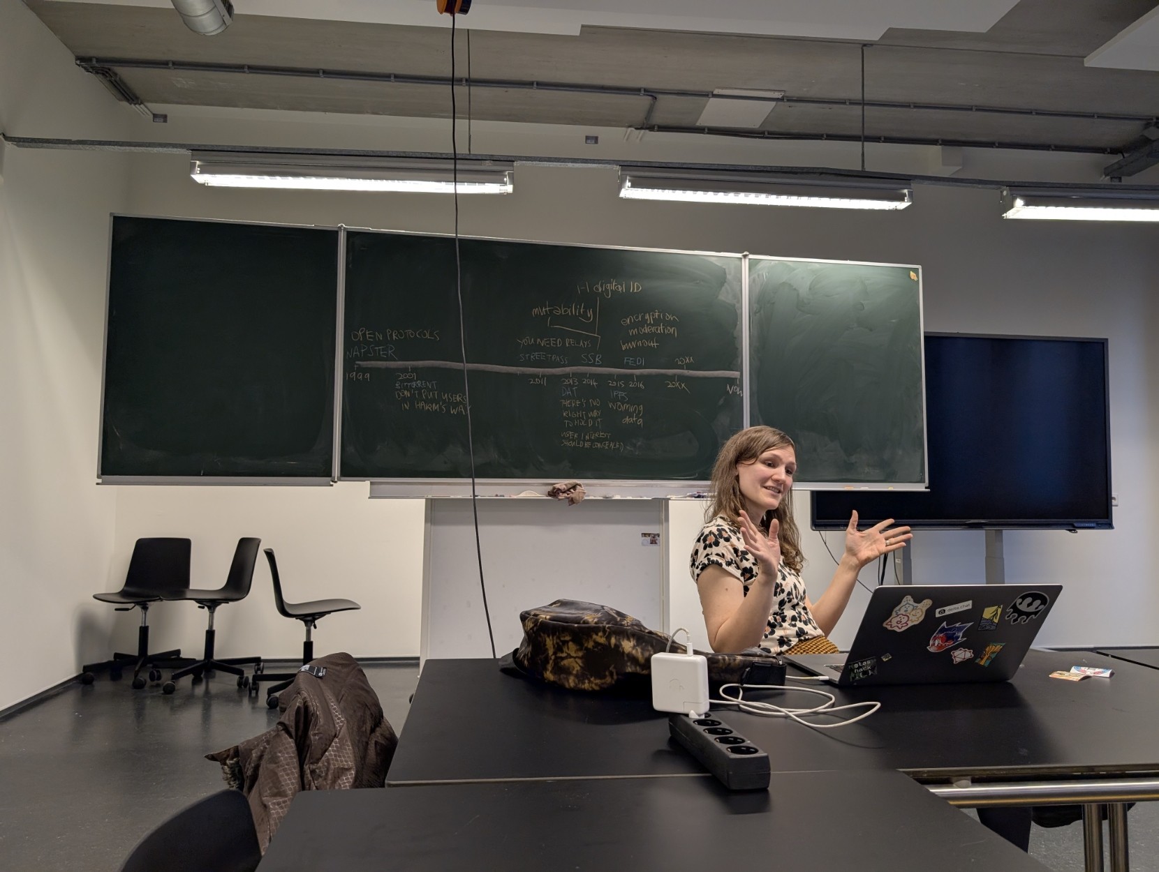 A blackboard with the timeline of decentralized tech since the 80s, and Sammy explaining in front of it